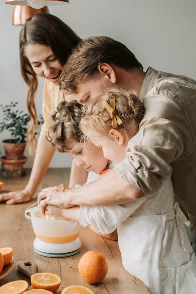 A family makes food together over a table.