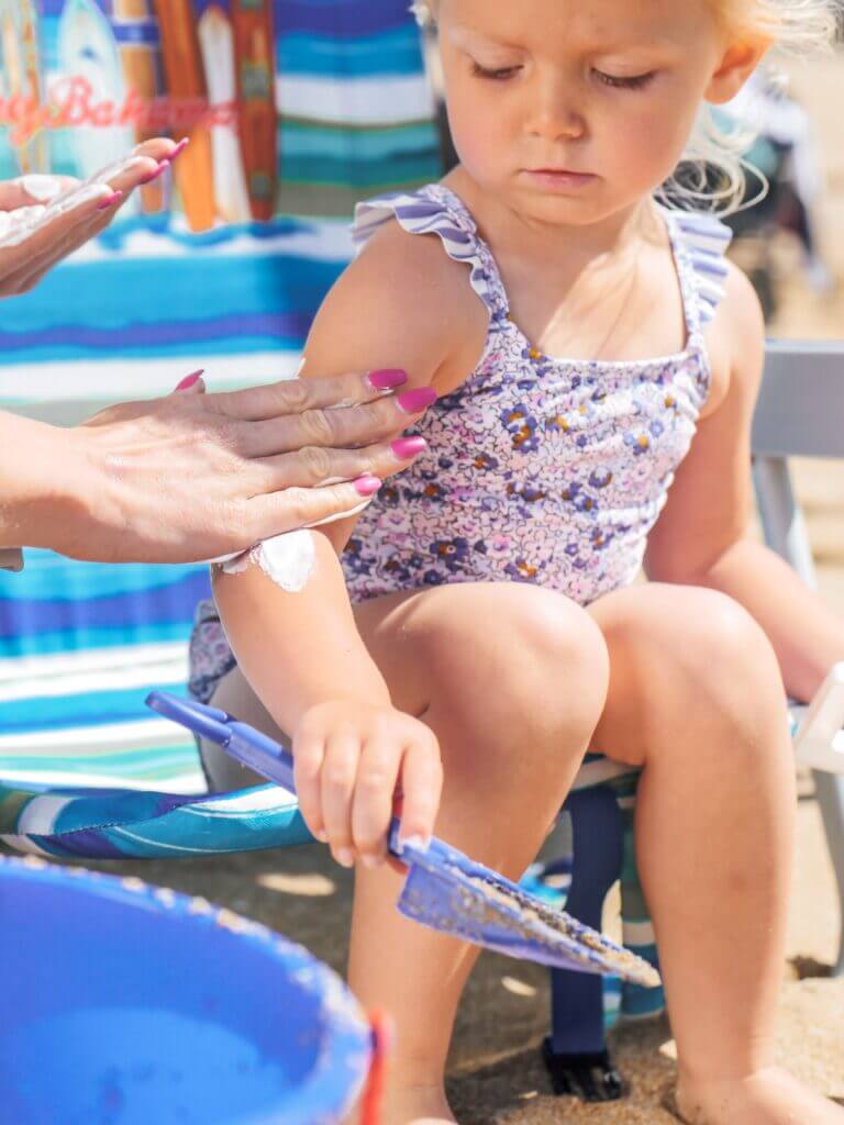 a toddler get some sunscreen put on at the beach a toddler get some sunscreen put on at the beach