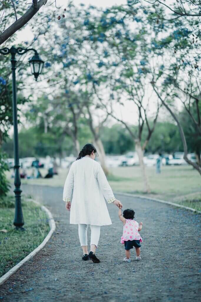 A mother and her toddler take a walk in the park together A mother and her toddler take a walk in the park together