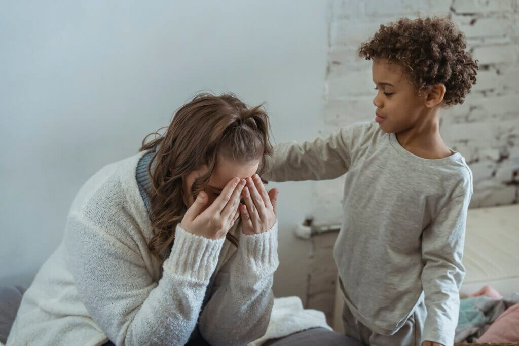 A woman fighting stay-at-home mom burnout on a couch while her son consoles her